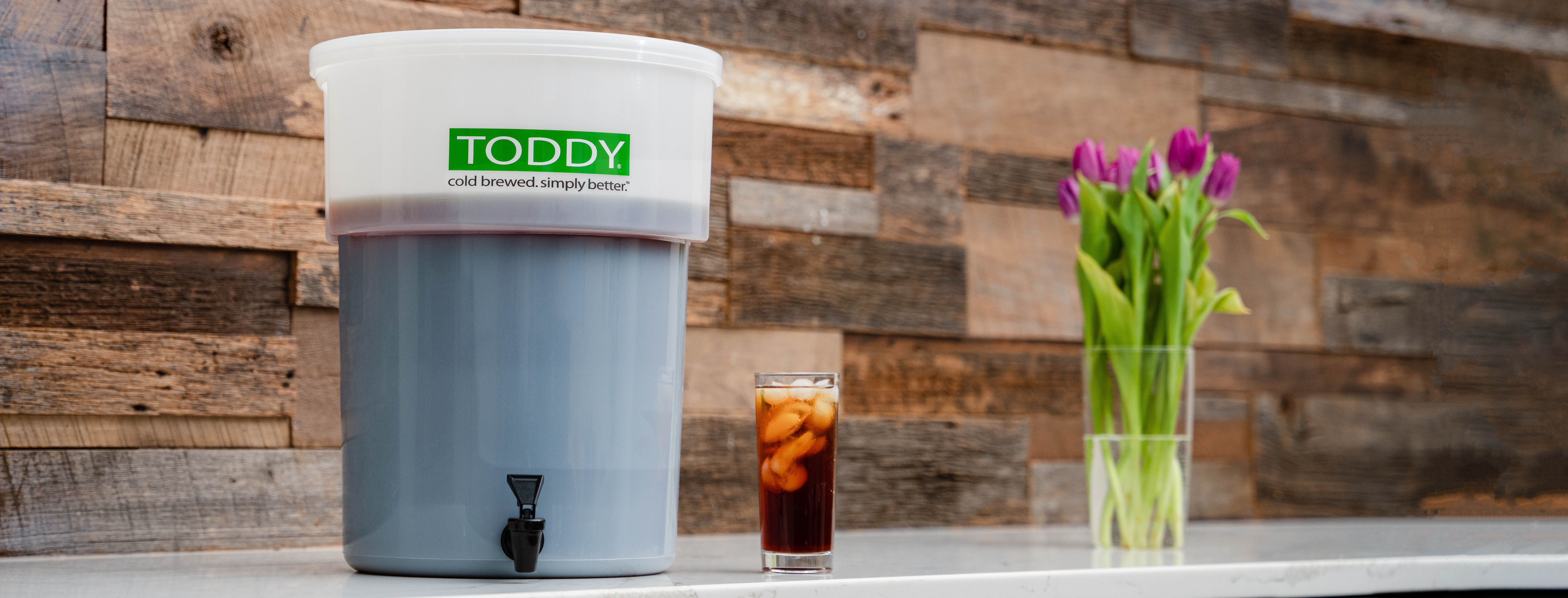 Toddy Commercial Model with beverage and tulips against wood backdrop